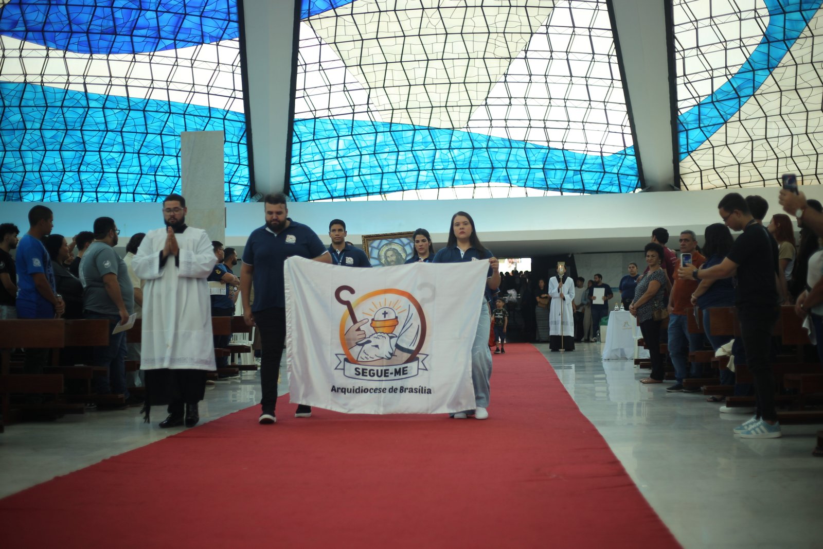Seguidores conduzindo a bandeira do SEGUE-ME em celebração na igreja